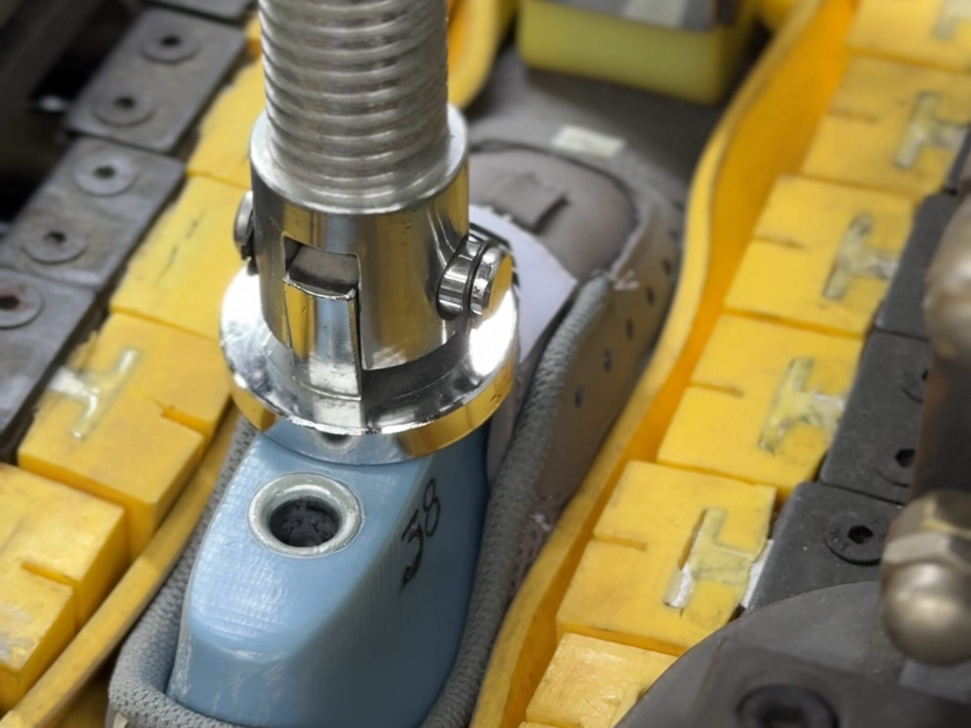 A lasting machine head pressing a shoe fitted on a blue last